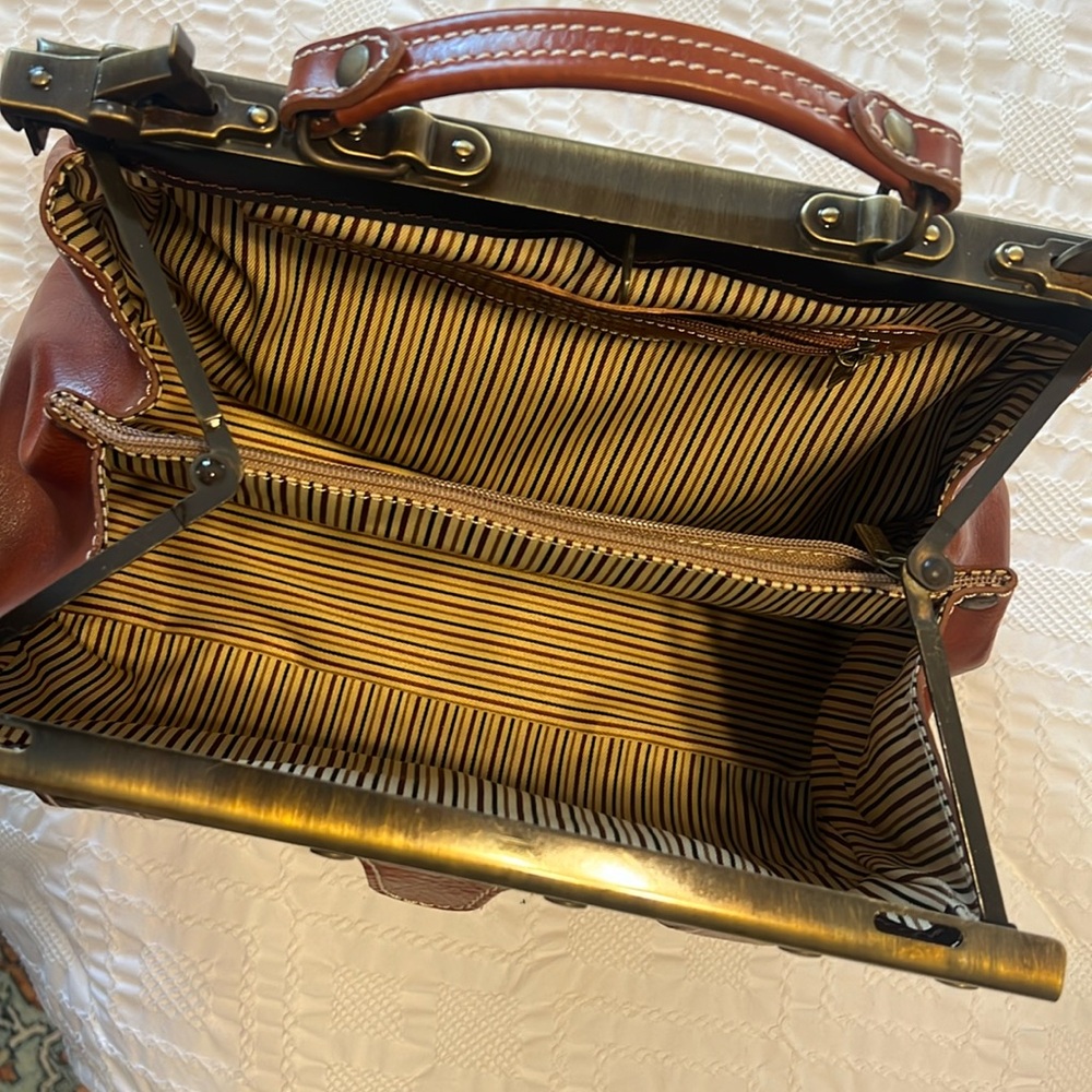 - Full grain leather
- Detachable shoulder strap
- Semi-rigid structure